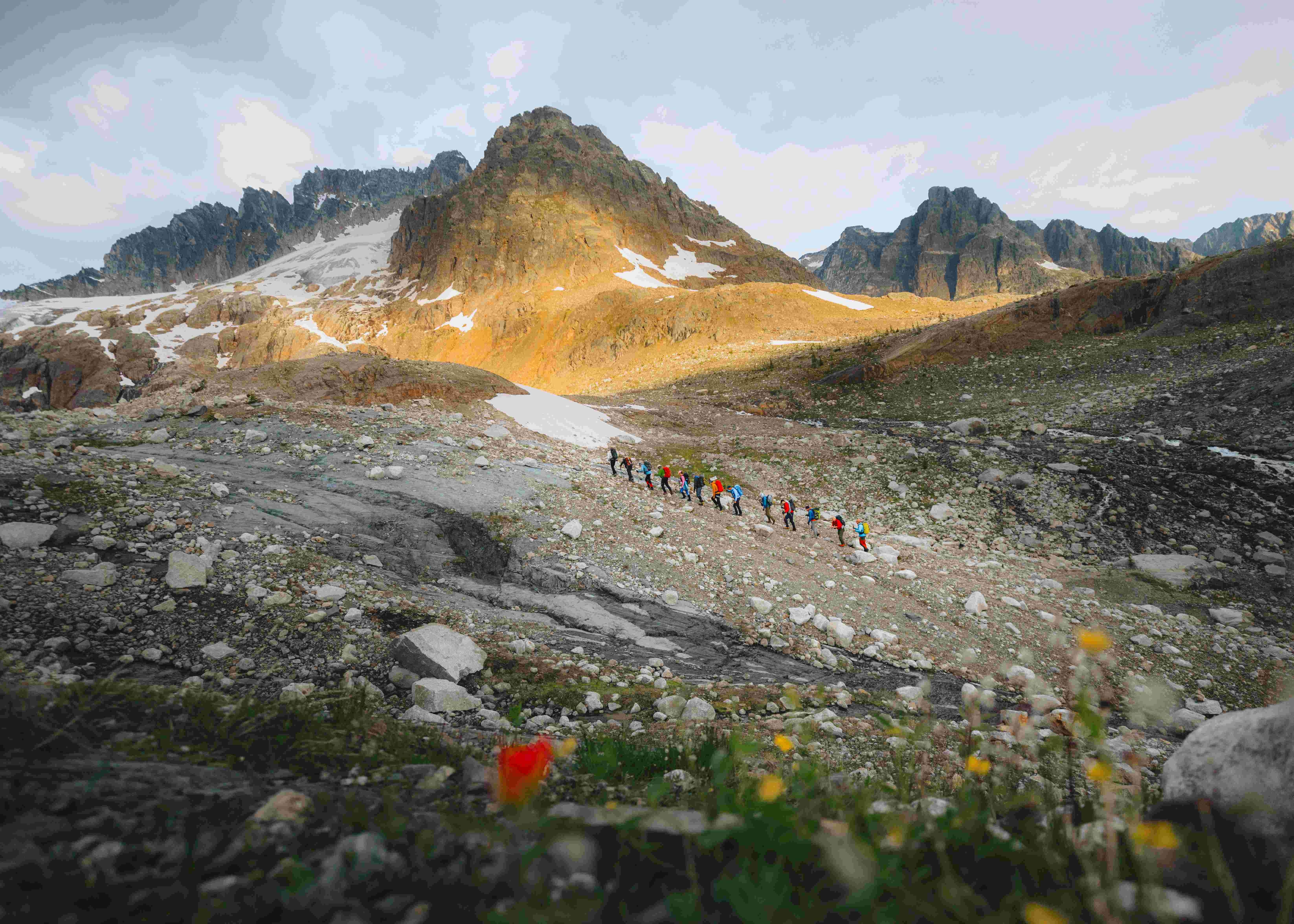 A group hikes over old rock moraines in the Canadian Rocky Mountains.