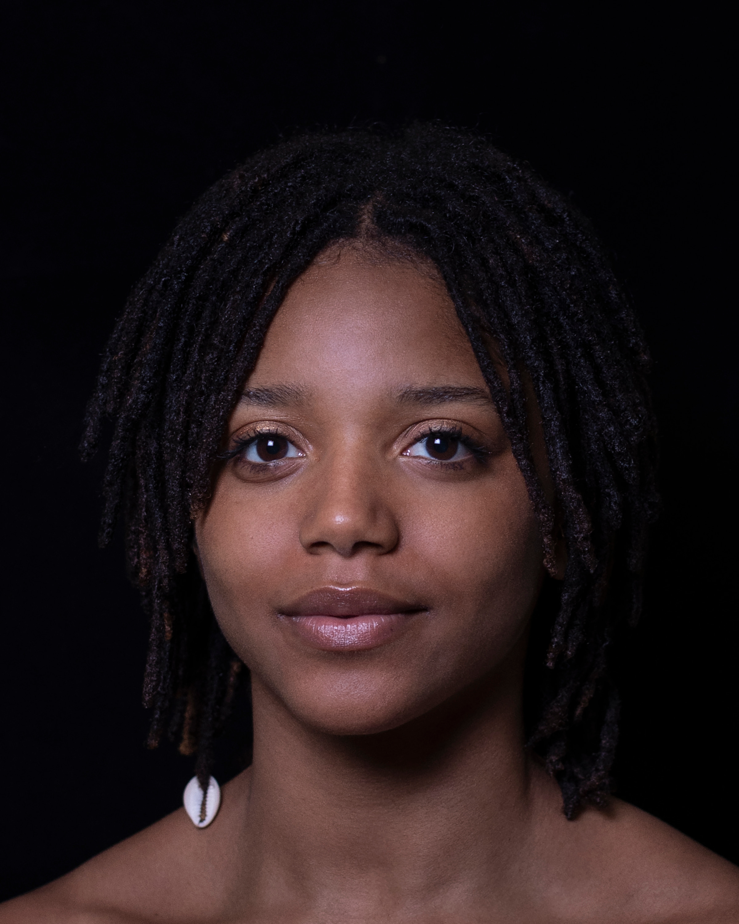 straight on portrait of woman smiling lightly at camera with dark background