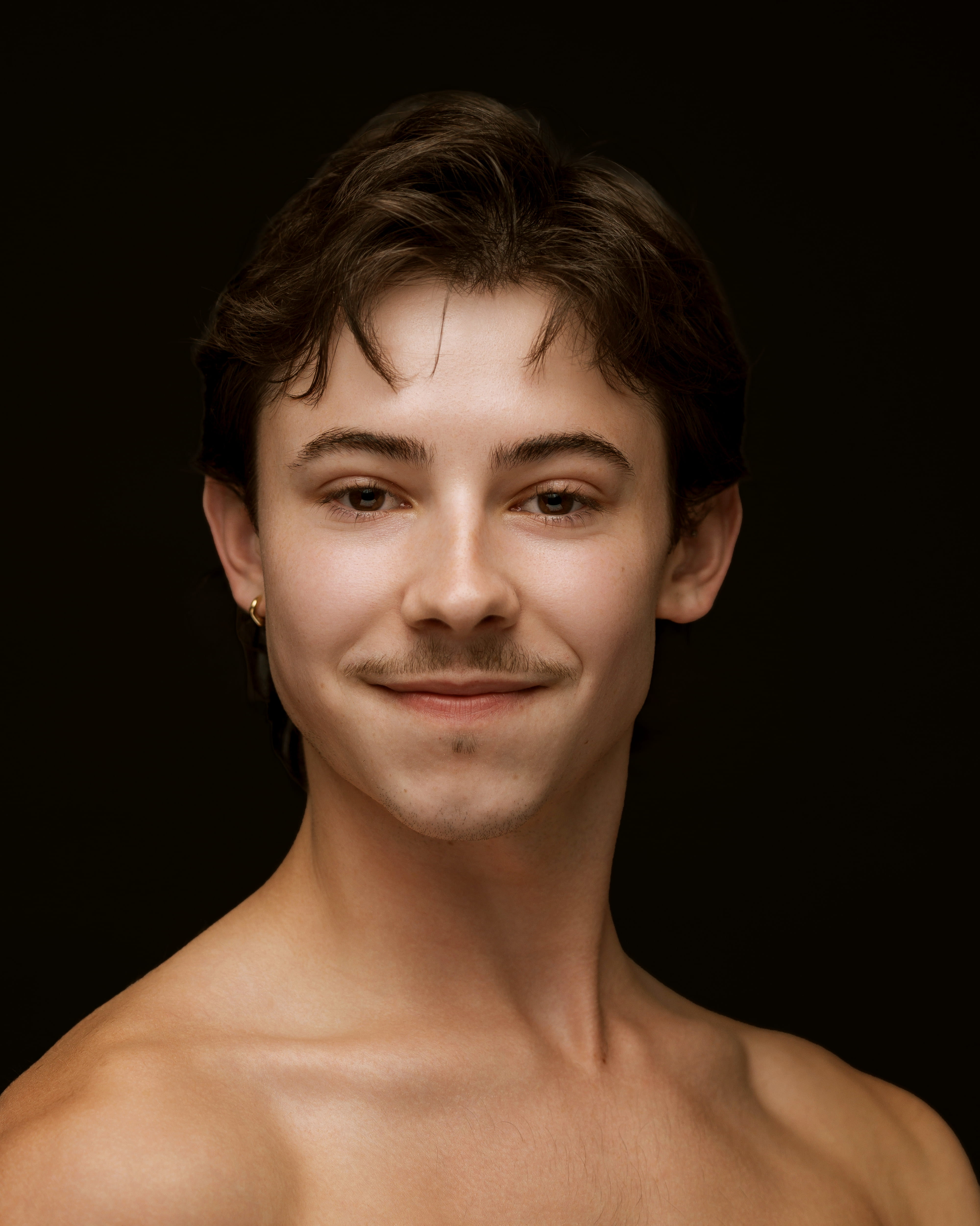 Dancer photographed from shoulders up facing the side with head turned toward camera
