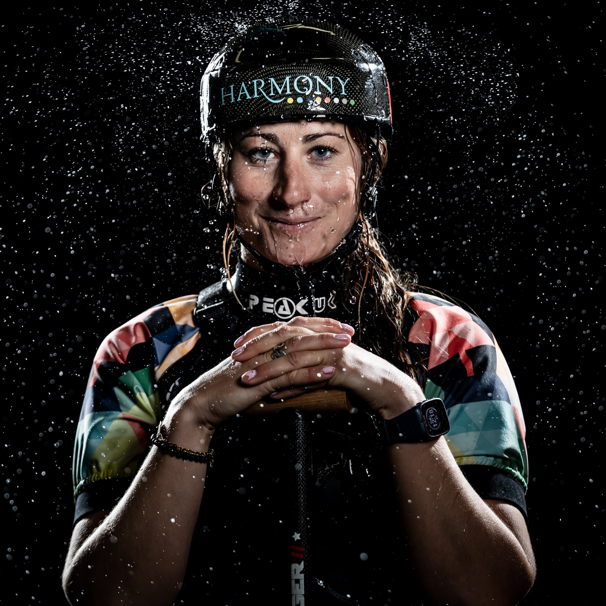 Athlete Hailey Daniels holds a paddle and smiles in a flash photo capturing water spray.