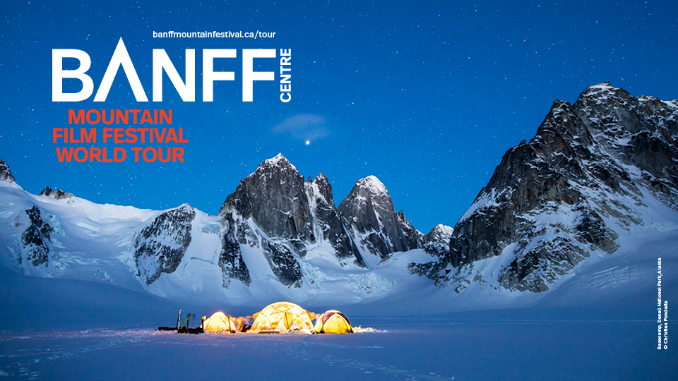 The 2021 Festival Signature Image: Three yellow tents sit on glacier at night, they are illuminated from within. Behind them granite peaks rise through the ice. 