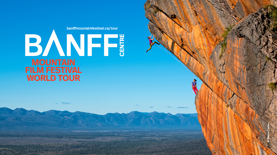 The 2022 Festival Signature Image: Two women climb on an wall of warm orange and grey rock in the Grampians, Australia. 