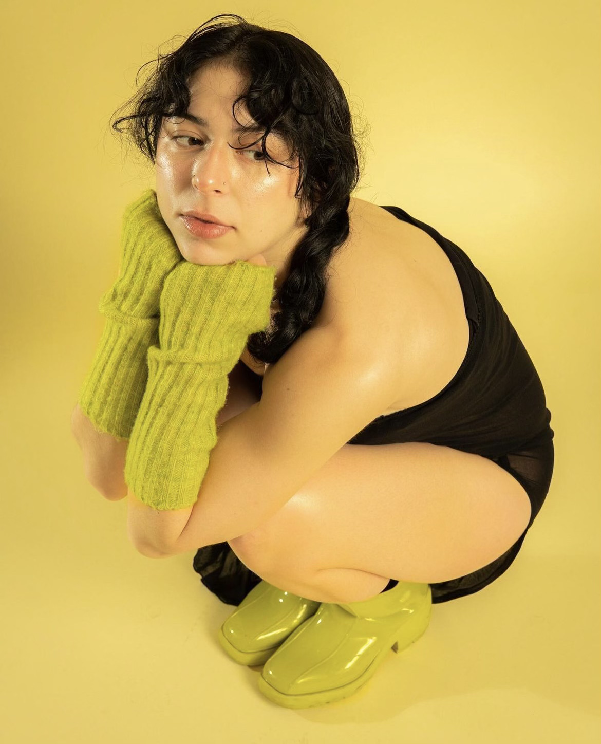 Women wearing green shoes and gloves, squatting 