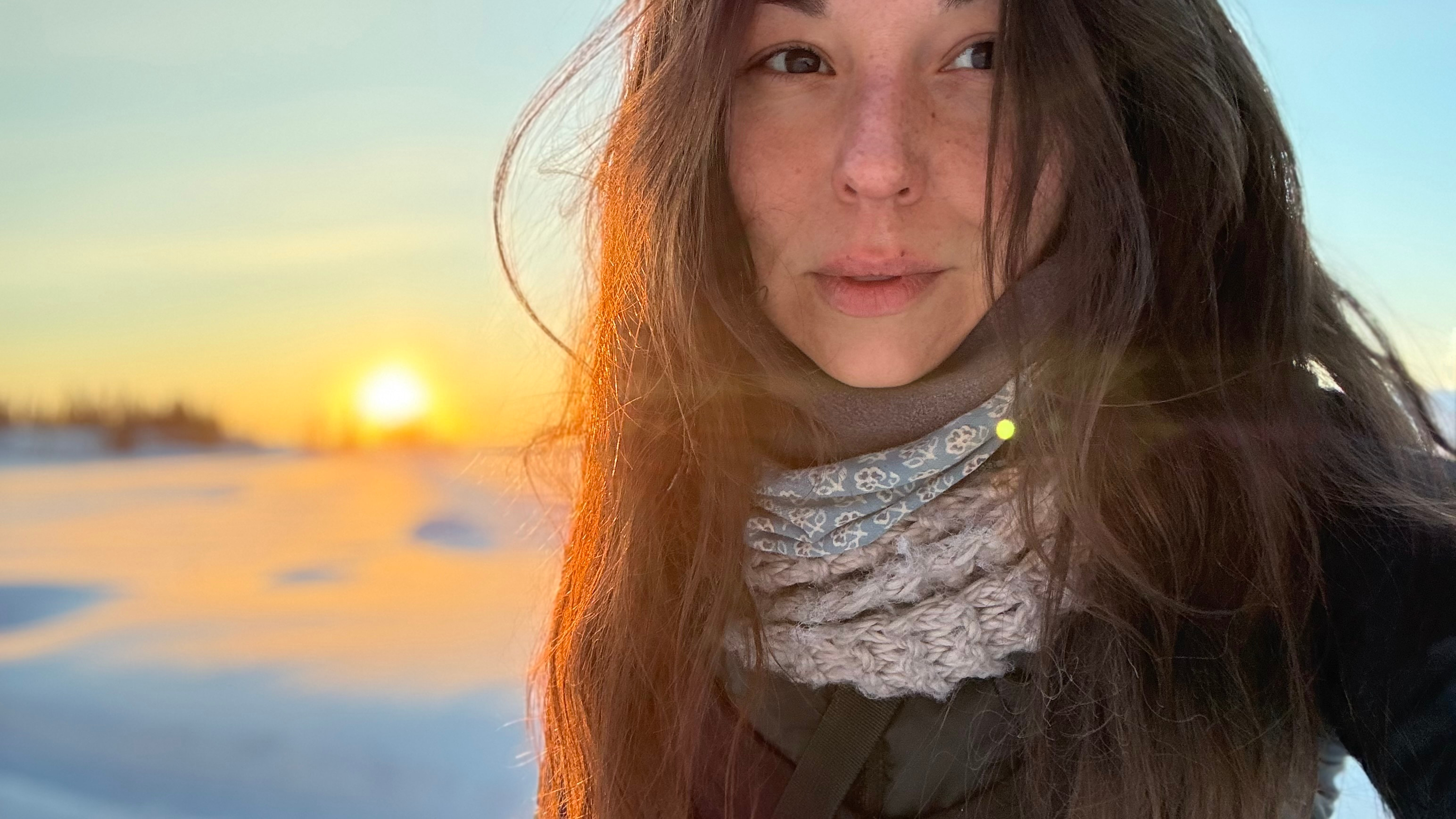 Women with long hair on the snow ground by sunrise