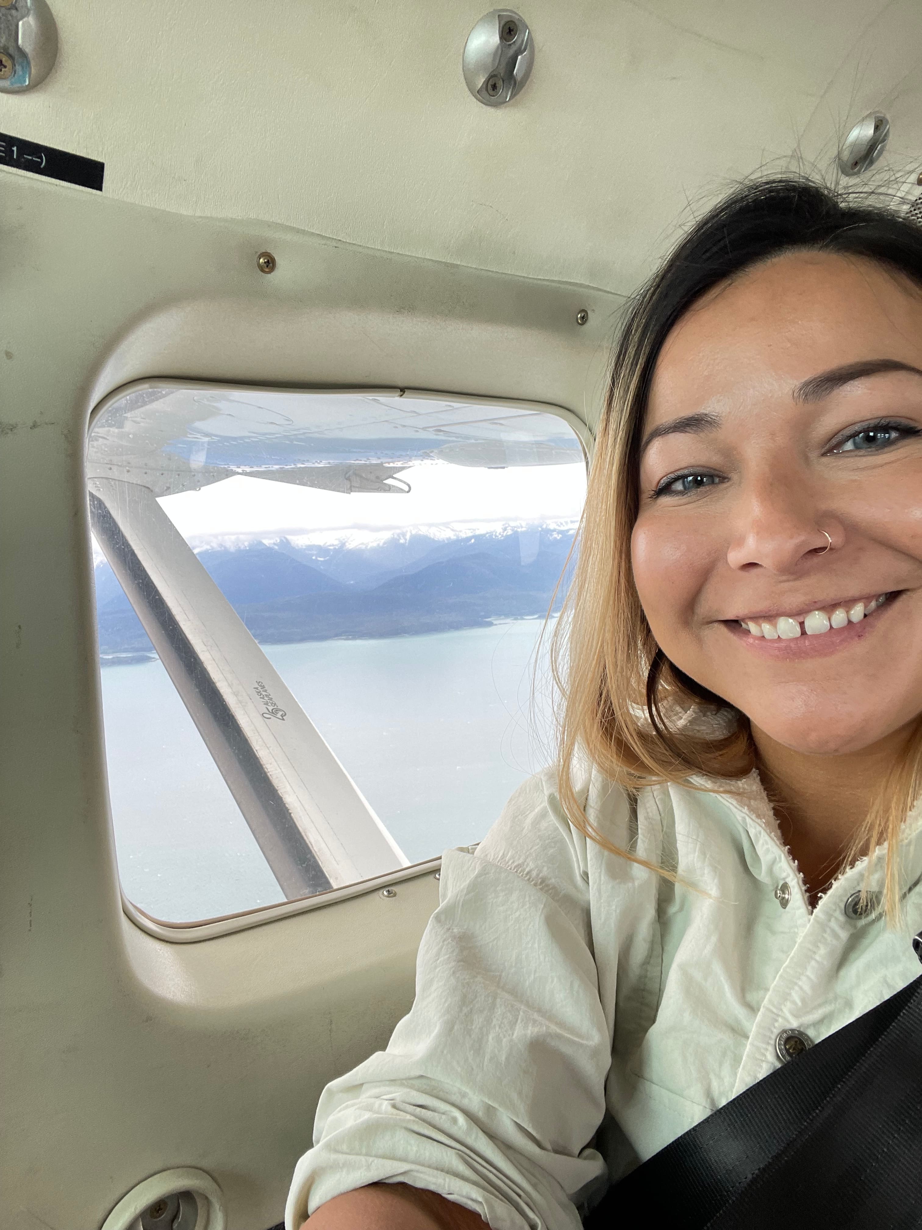 Women smiling in an airplane flying over the ocean 