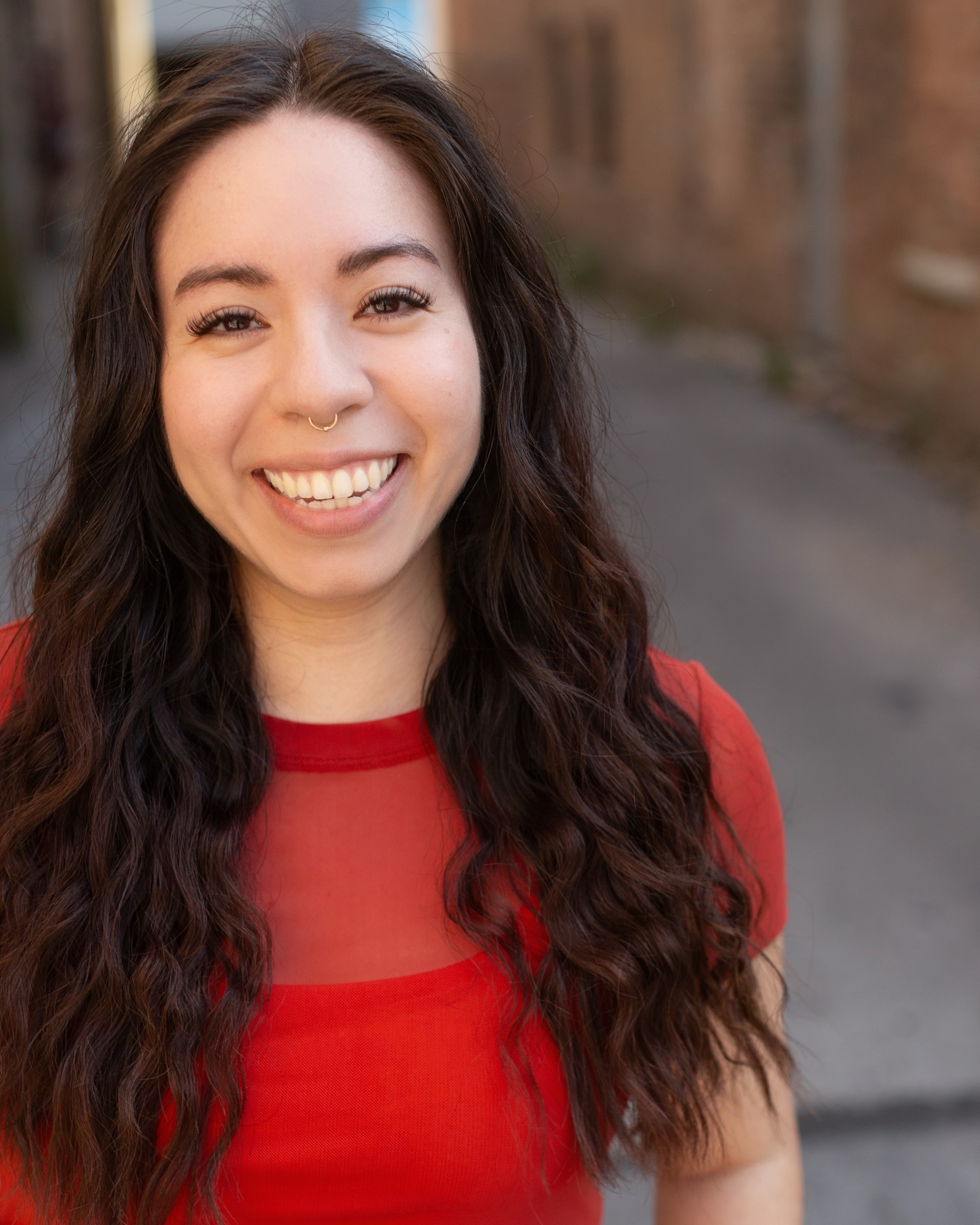 Women smiling with long and curly hair wearing a red t-shirt