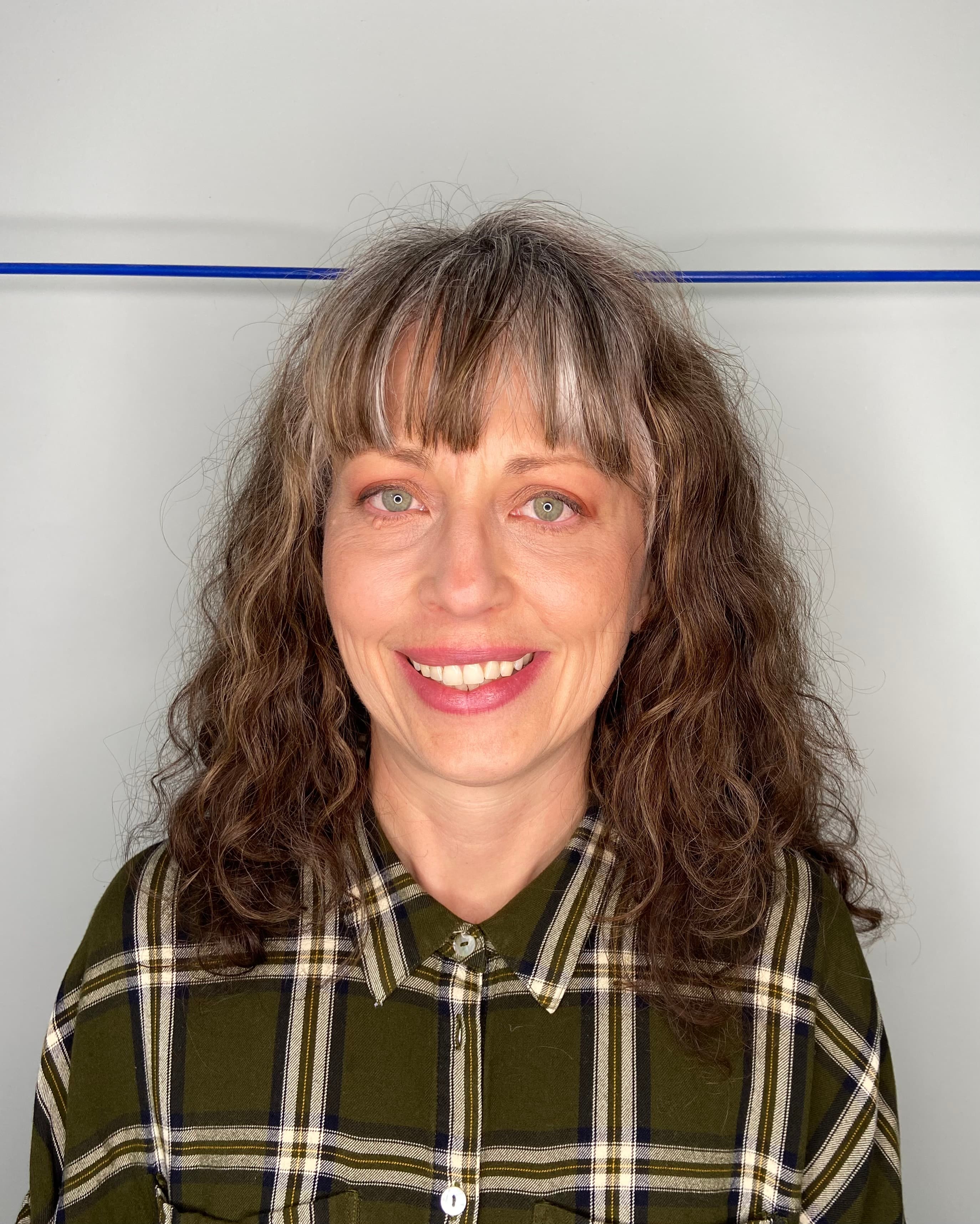 Woman with long hair and bangs smiling and looking straight at the camera