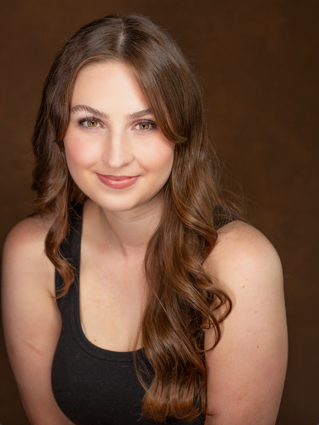 Woman with long blonde wavy hair falling over her shoulders and smiling directly at camera