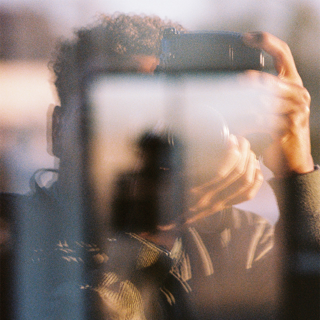 Men with camera shooting and being in the reflection of glass