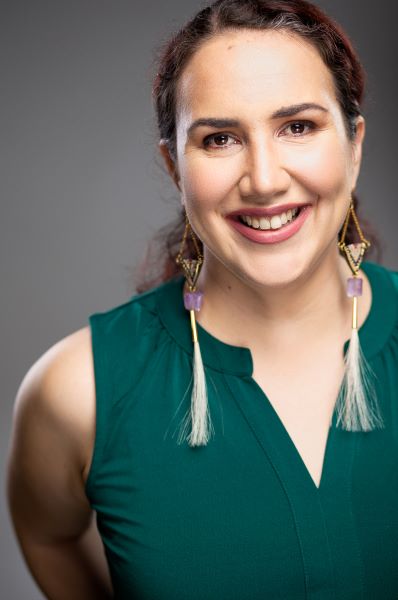 Brunette woman in a green sleeveless top smiles at the camera