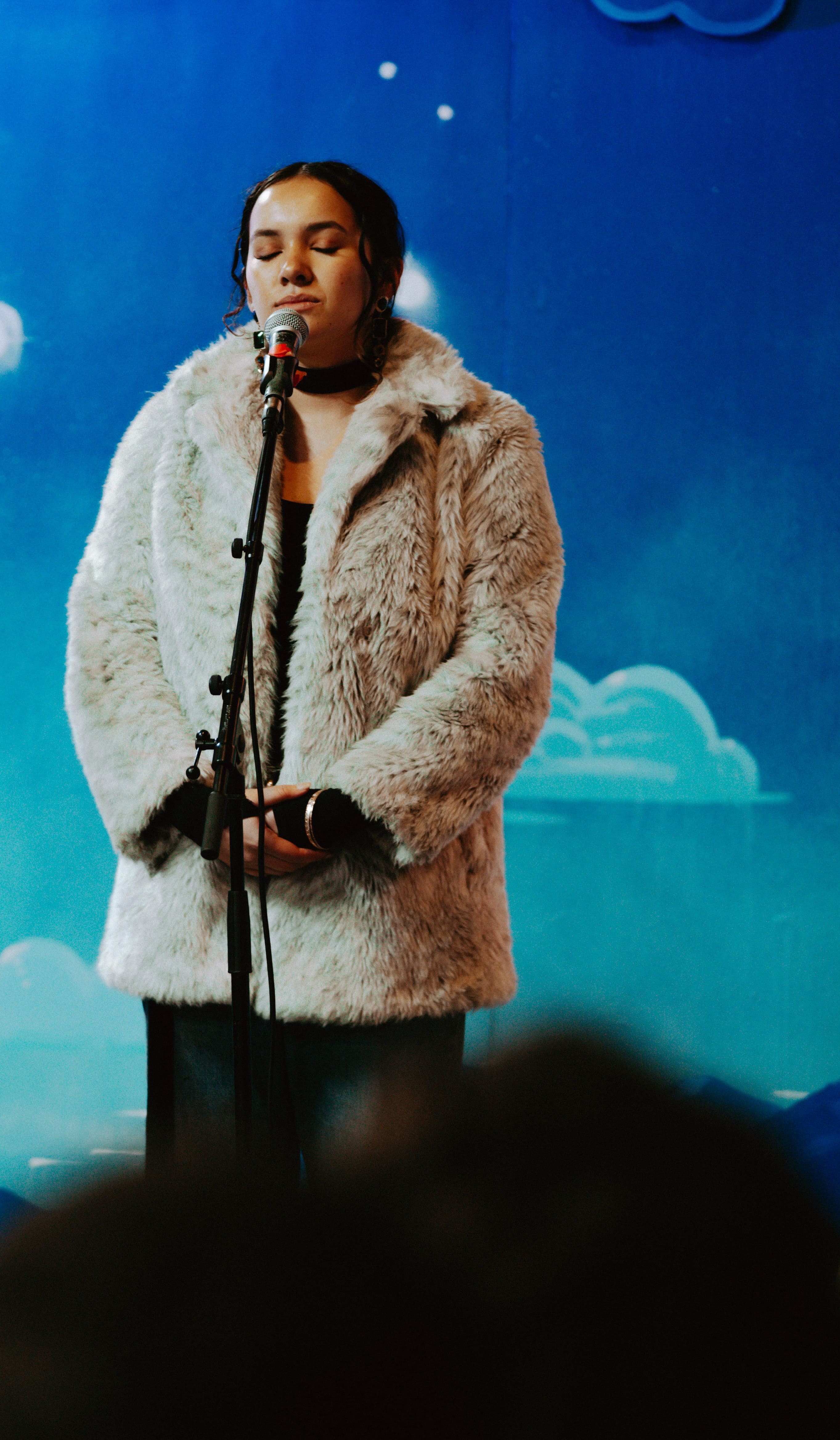 Women in fur coat performing in front of a microphone 
