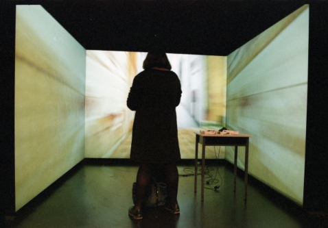Woman stands before three wall sized screens