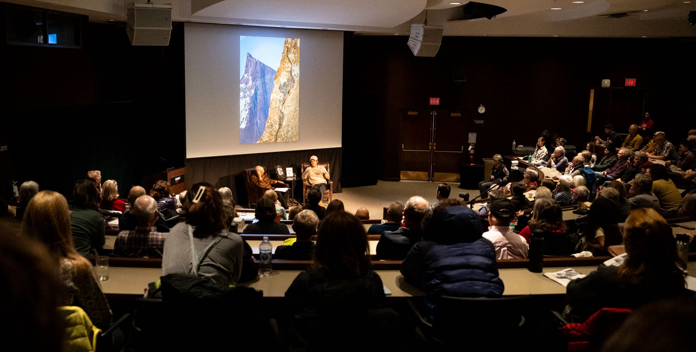 Audience sitting around two speakers at an event in an auditorium at Banff Centre.