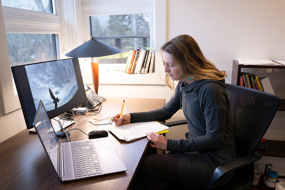 A writer is working at a desk in front of a window