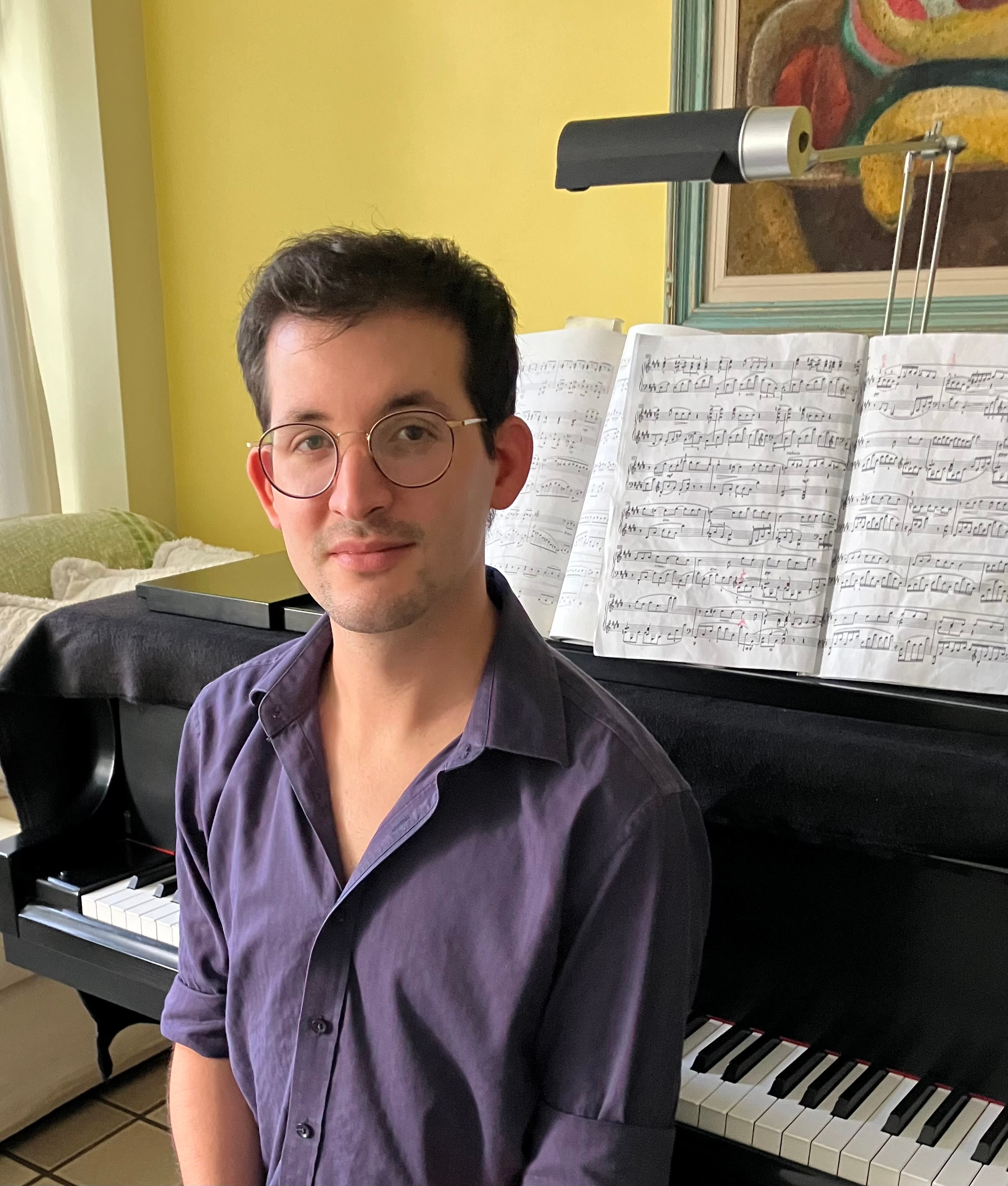 Man with short hair sitting in front of a piano