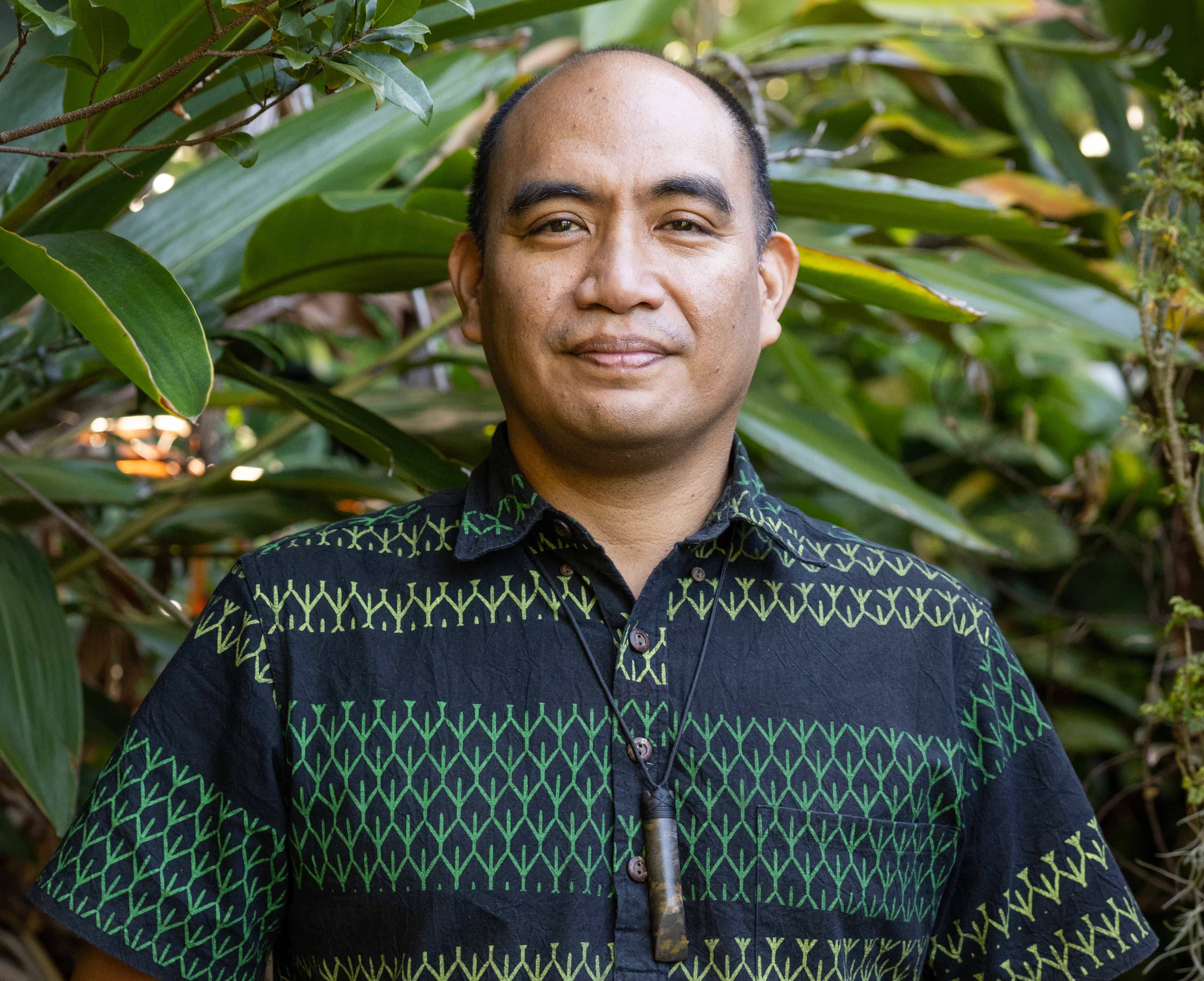 Indigenous Hawaiian men wearing green patterned shirt standing in nature