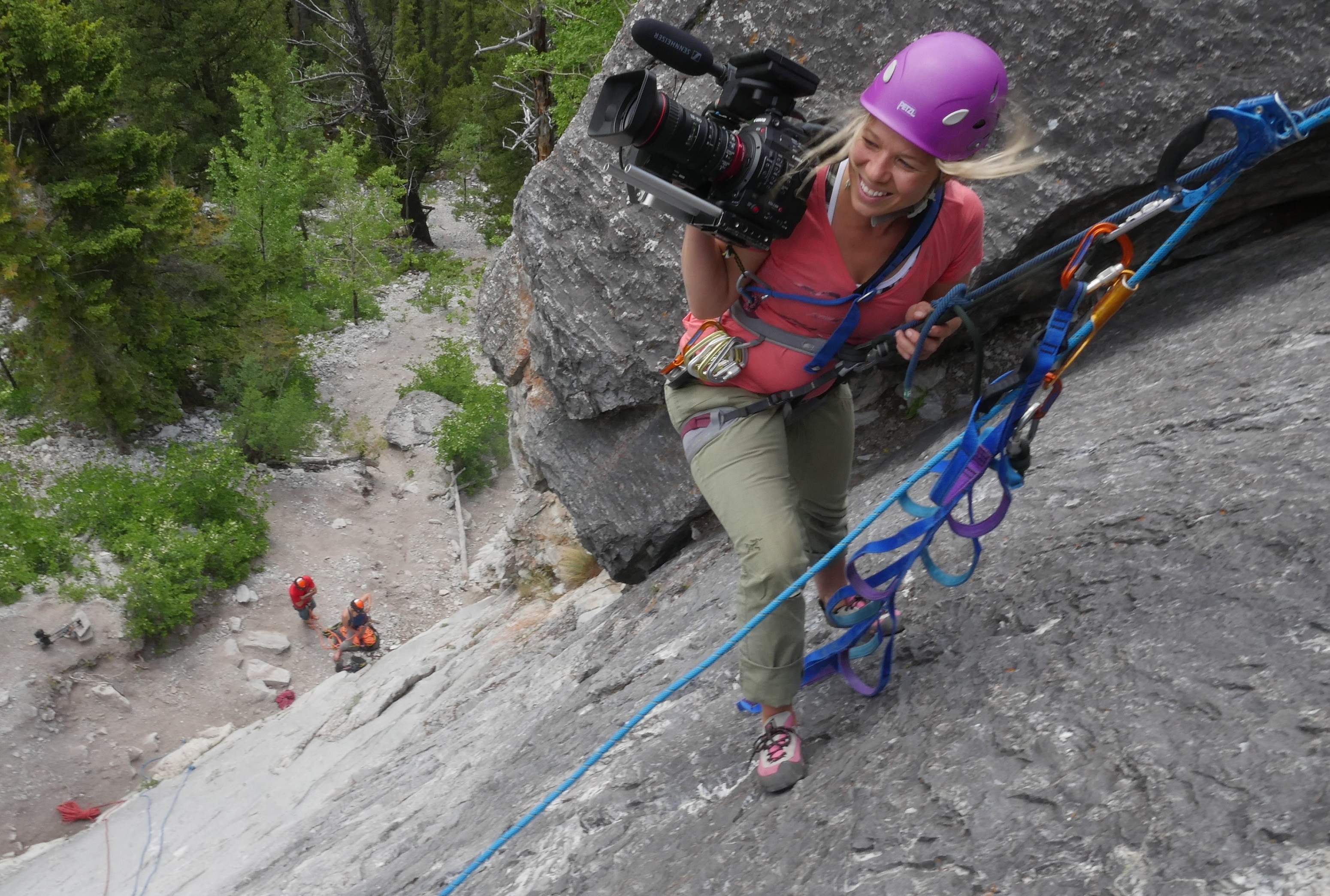 Filmmaker rock climbing with filming equipment