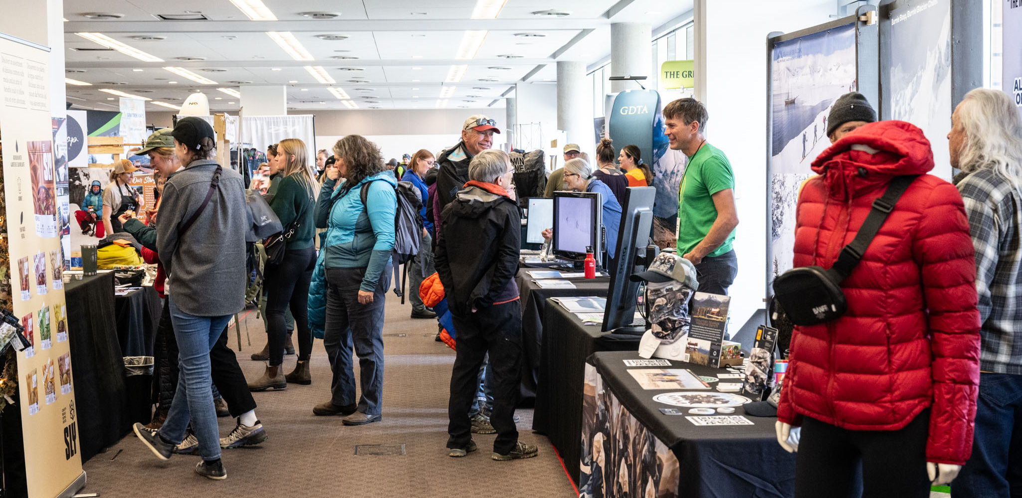 A large number of people engage with exhibitors at their booths in a crowded Marketplace?