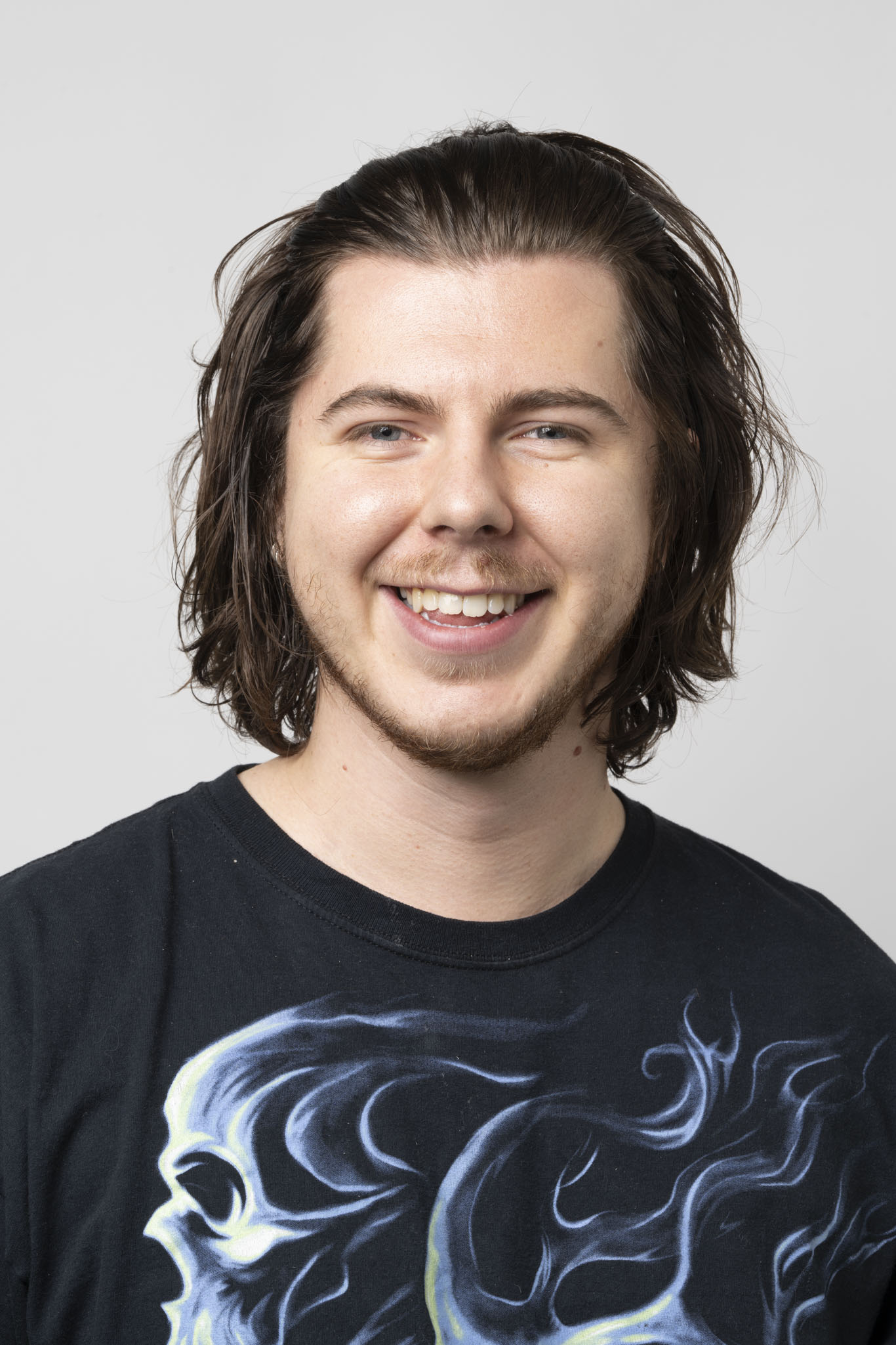 Man with shoulder length hair smiling broadly at camera