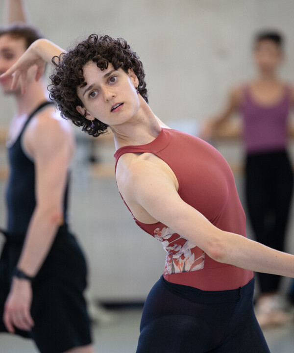 A dancer in a pink leotard dances in a studio