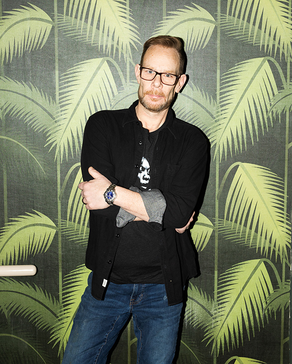 DJ Rob Faust standing against palm tree pattern wall paper