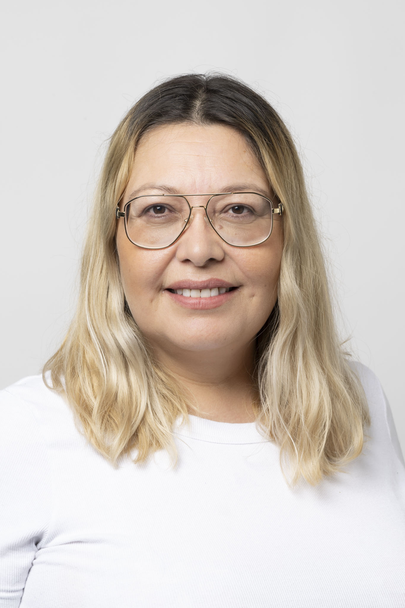 Woman with blonde shoulder length hair and glasses smiling directly at camera