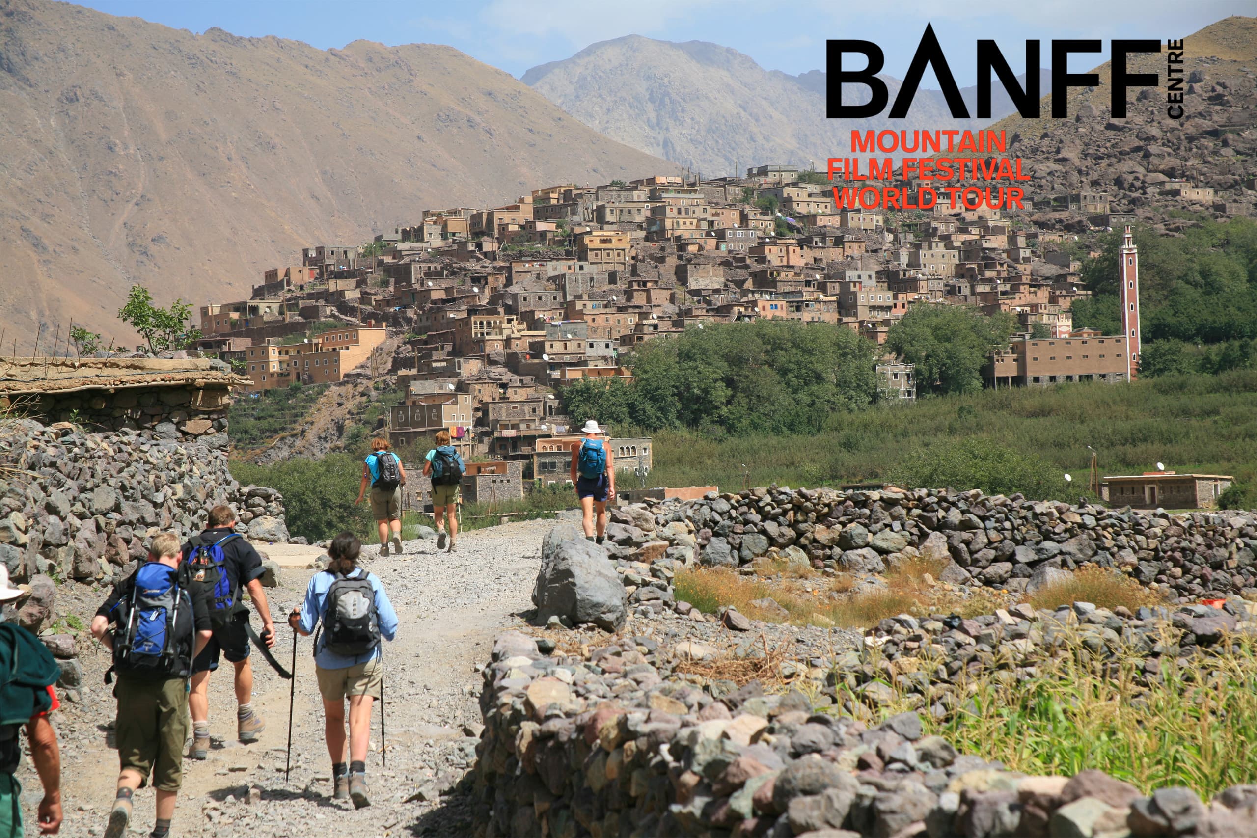 Group of hikers approaching settlement surrounded by mountains