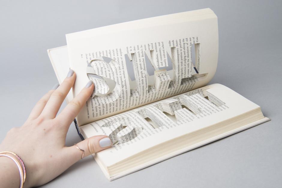 Image of hand holding open an artists' book.