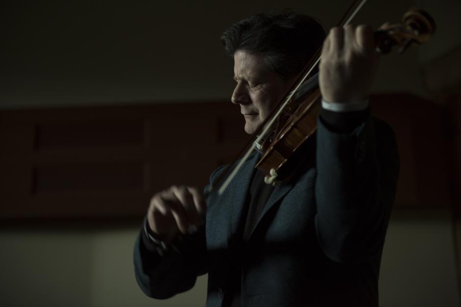 Barry Shiffman playing the violin in a dark theatre. 