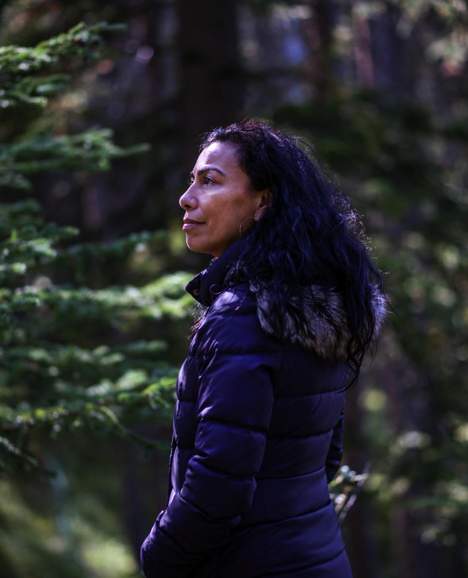 Carmen Aguirre looks into the distance while surrounded by trees. 