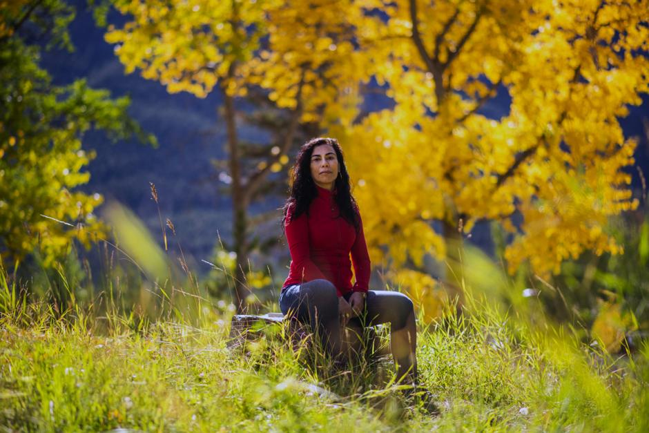 Artist Carmen Aguirre poses in a colourful forest in the fall. 
