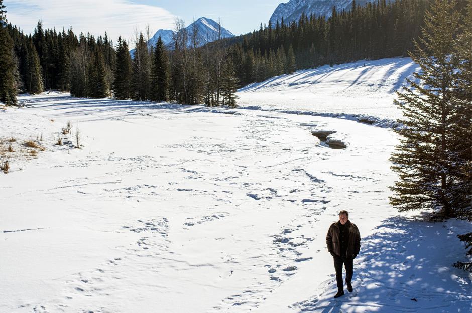 Jean Grand-Maître walks along a snow covered river. 