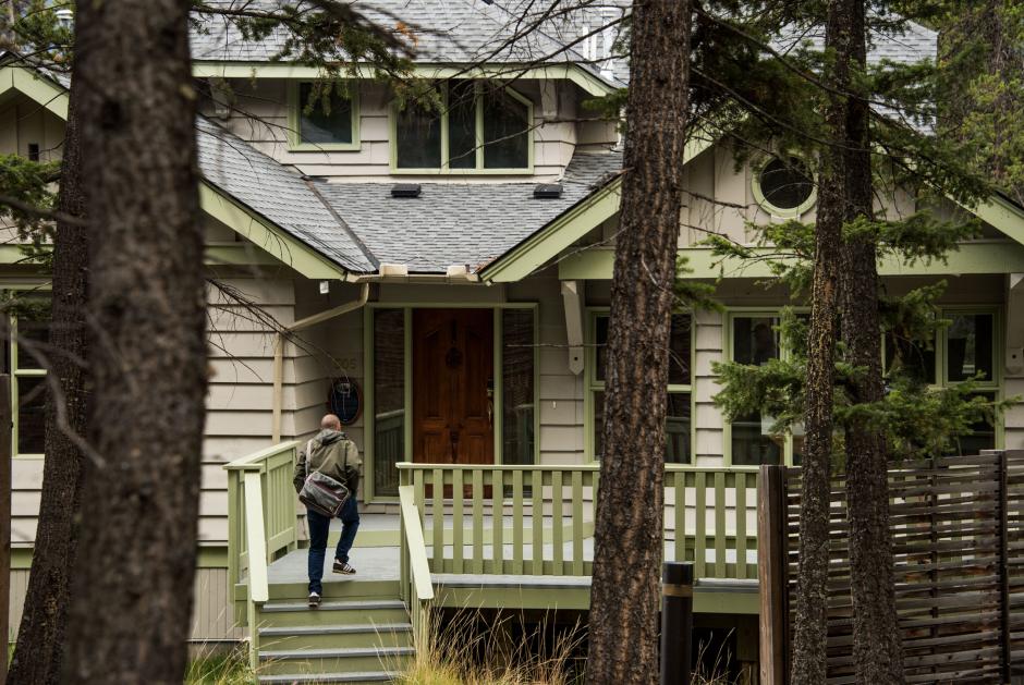 Man walking into a house in the woods.