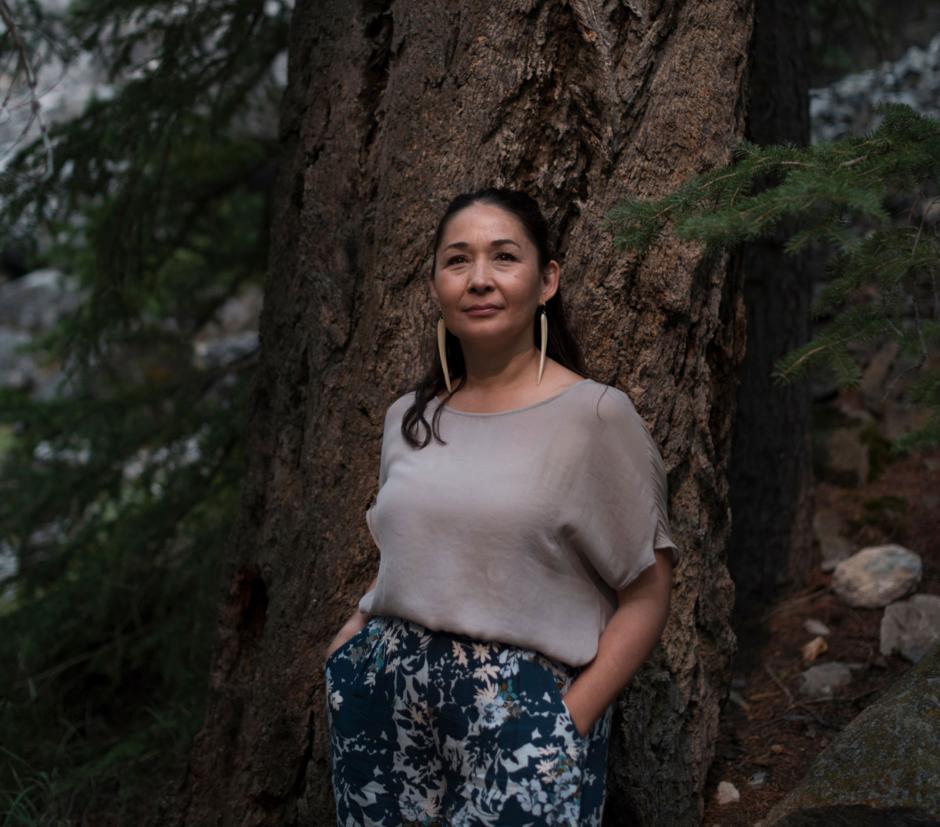 Reneltta Arluk | Banff Centre Female Artist poses in front of a large oak tree.