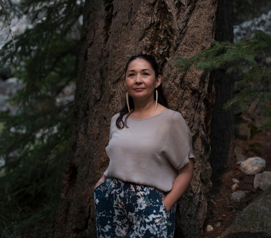 Female Artist poses in front of a large oak tree. 