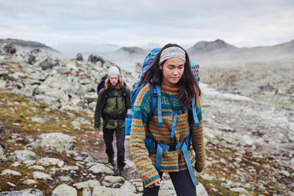 Hikers wearing Buff headwear on a misty morning hike over craggy terrain.