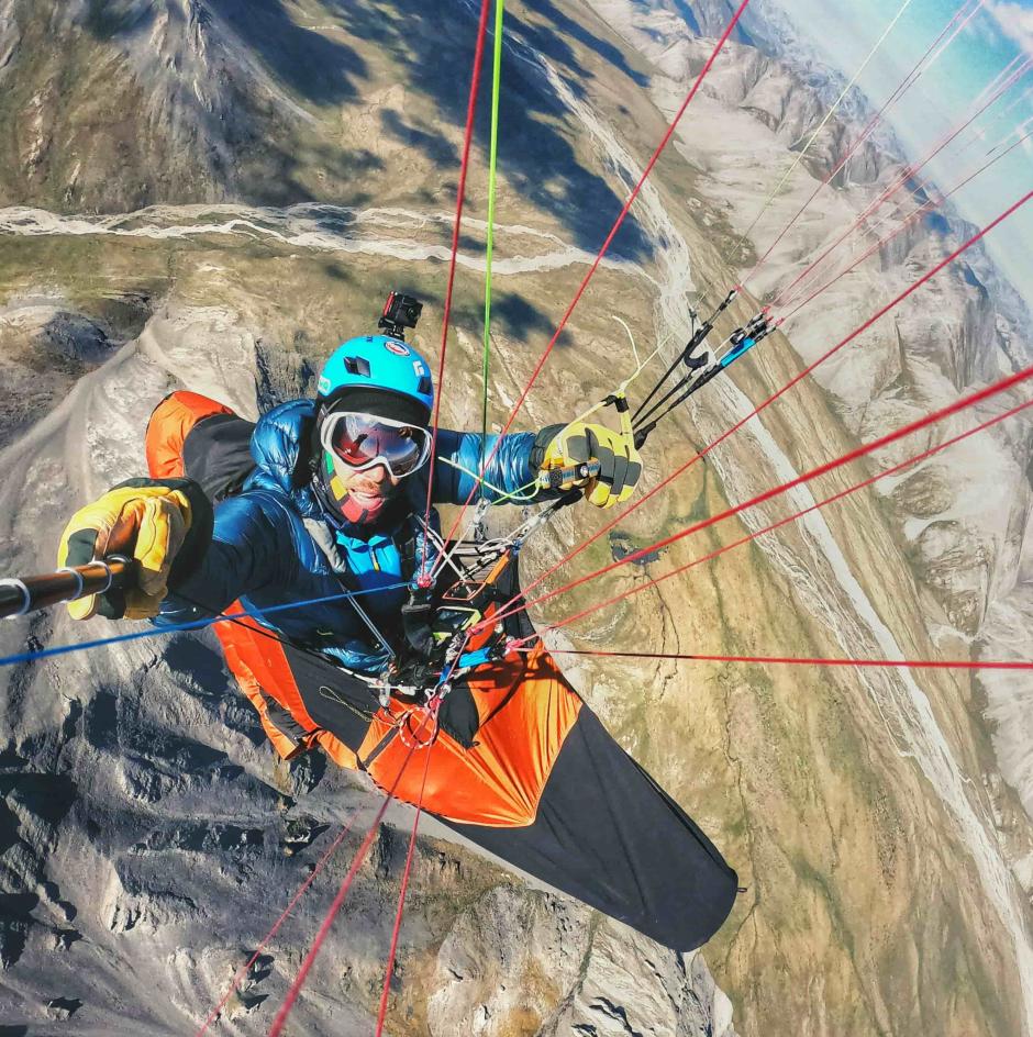 A paraglider is flying over mountains.