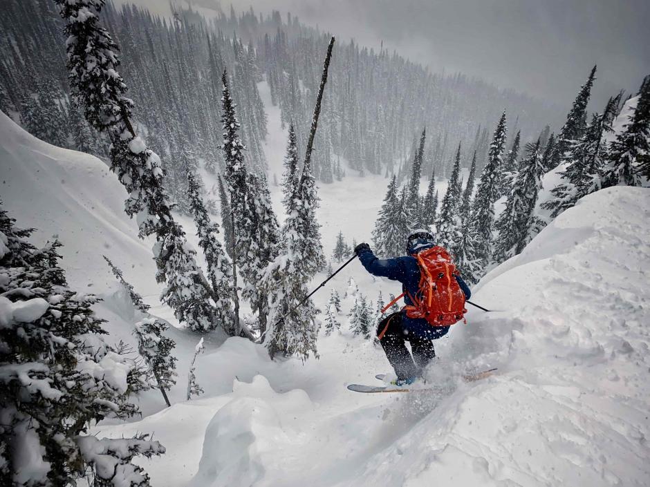 A skier is dropping off a cliff into deep powder 