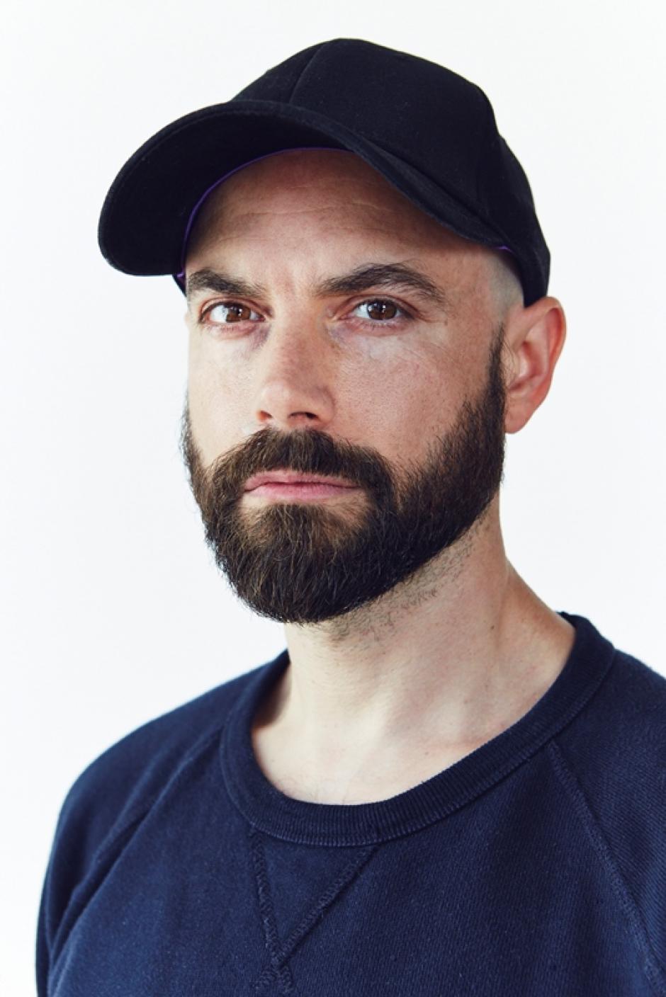 Chris Curreri Portrait staring at photographer in navy ball cap and shirt.