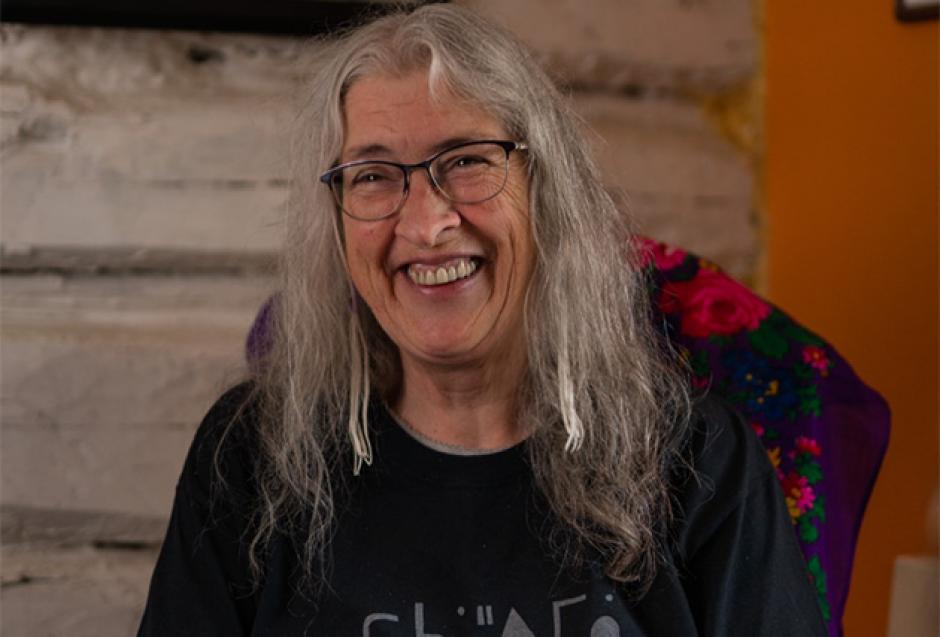 Marjorie Beaucage is seated on a chair and smiling at the camera