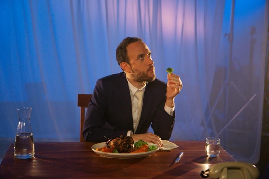 Michael Portnoy sits at a staged table comically holding broccoli.