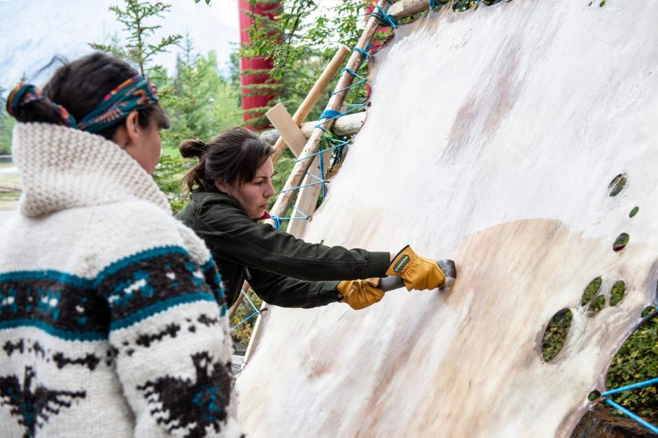 An indigenous artist works on a hide during a residency. 