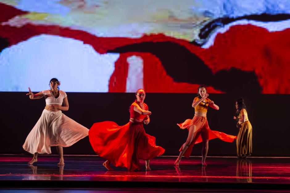 Four dancers performing in costume on stage.