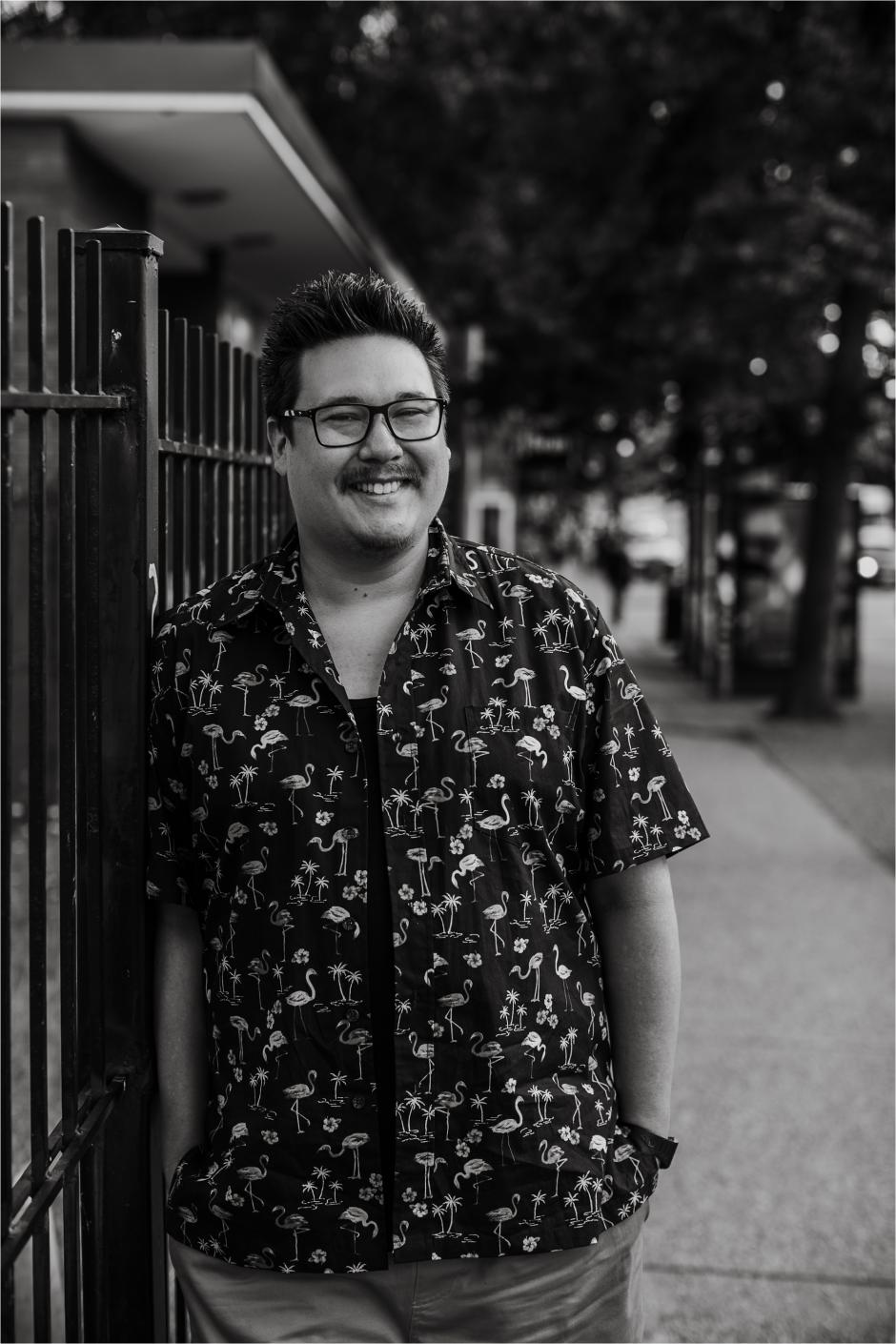 Writer Jordan Abel stands on a sidewalk and smiles at the camera