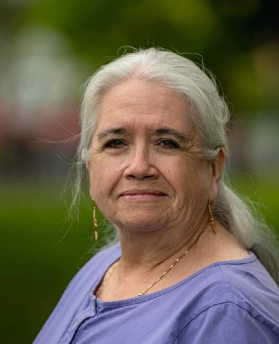 Writer Michelle Good stands outside against a blurred green background