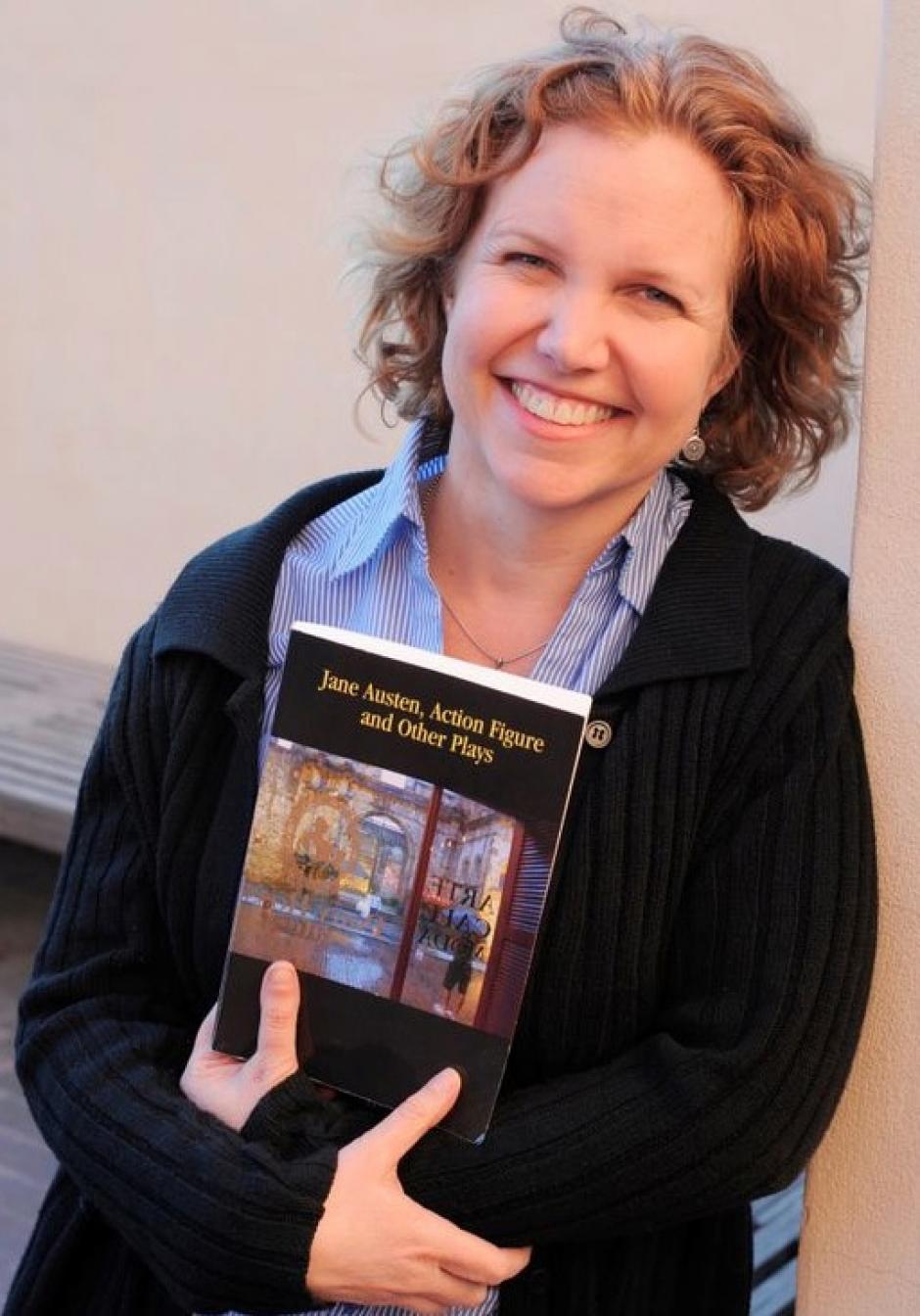 Elaine Avila is holding a book in her arms and smiling at the camera