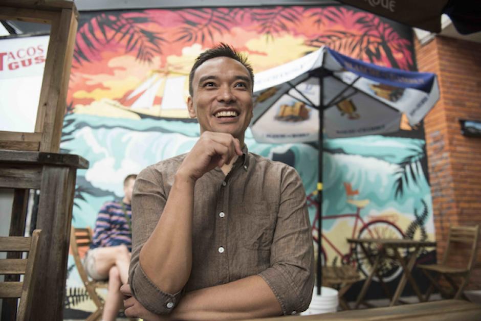 Michael Caldwell stands smiling in front of colorful mural