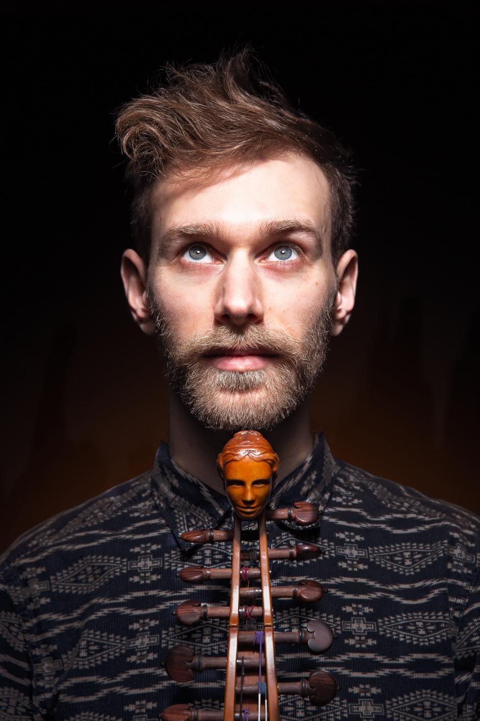 Musician Jaron Freeman-Fox looks up while holding an instrument under the chin