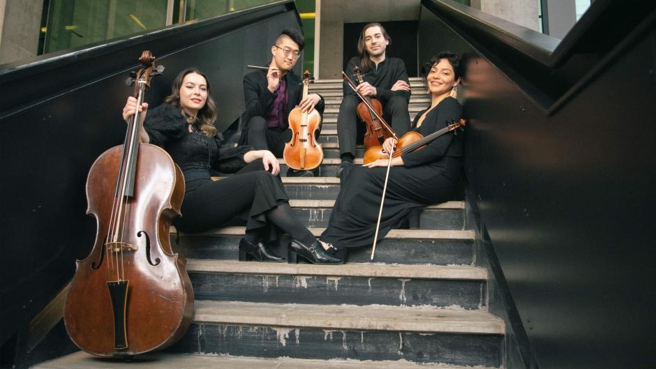 The Ximenez Quartet sits on stairs holding their instruments. They smile at the camera. 