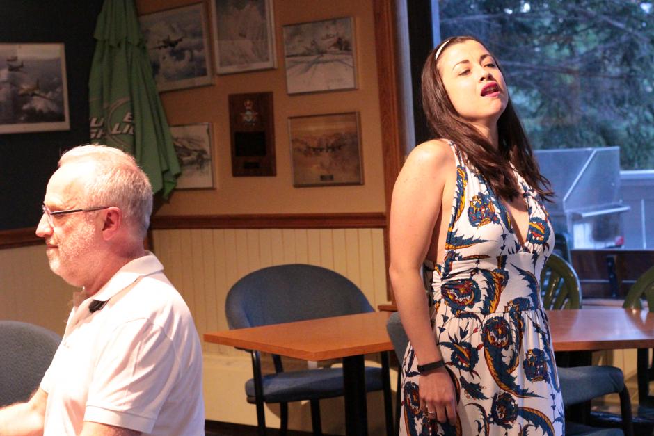 Woman in dress sings while man in white shirt plays piano